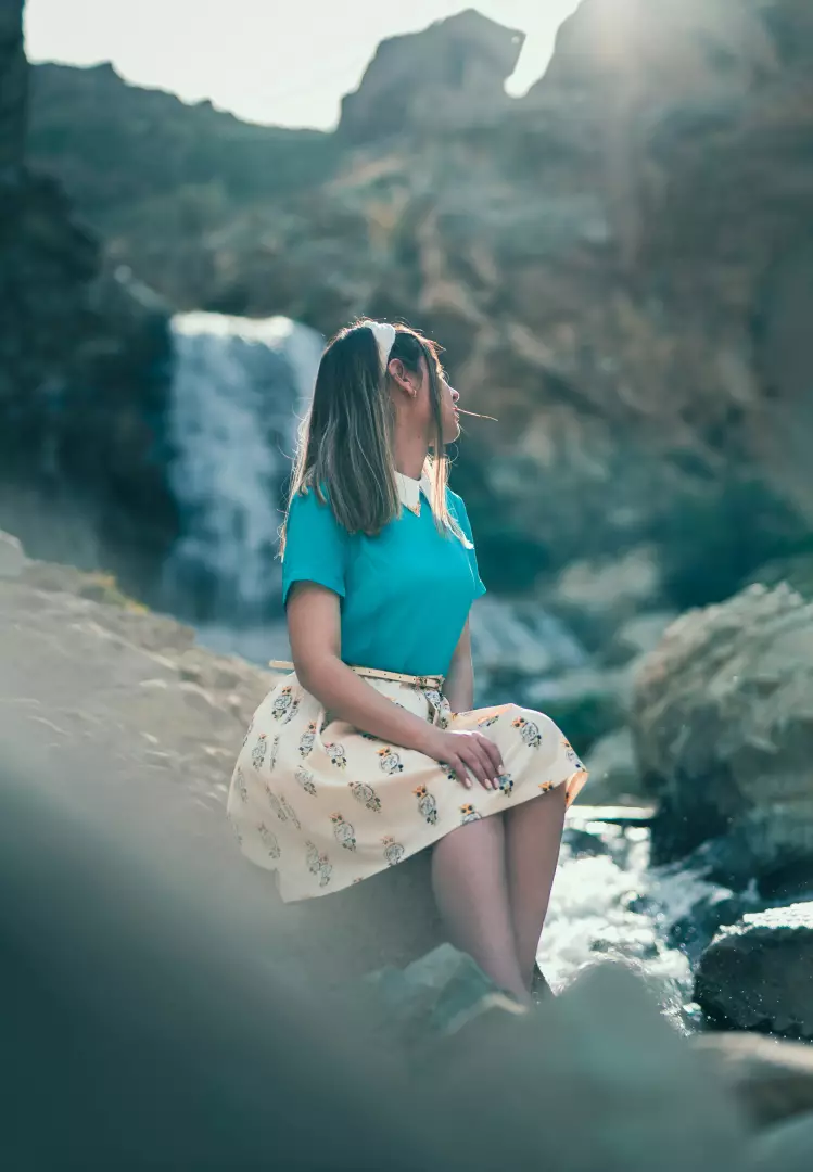 Free Premium Stock Photos Young Woman in Teal Shirt and Patterned Skirt Relaxing by a Natural Waterfall