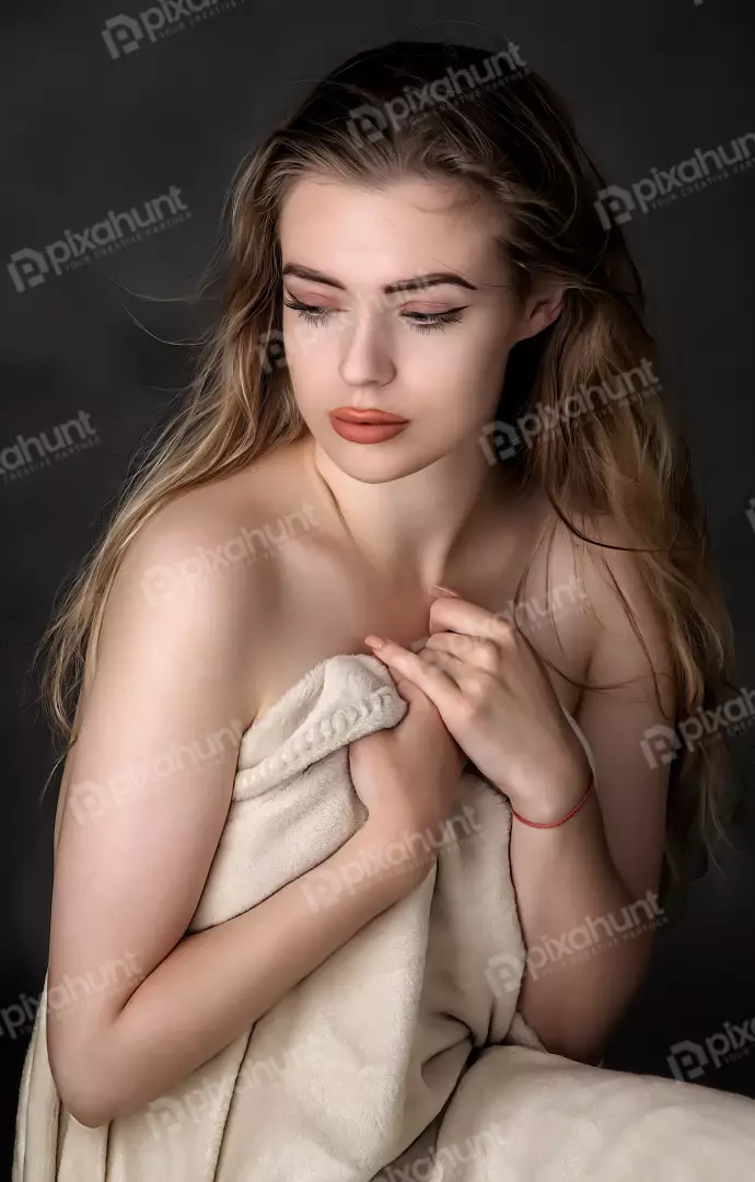 Pensive Young Woman Draped in Soft Blanket with Downcast Gaze