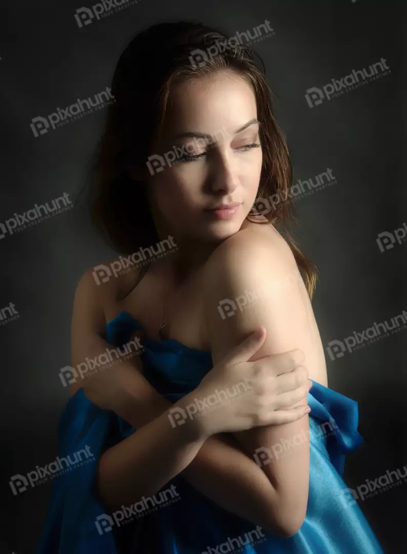 Pensive Young Woman Draped in Blue Silk Fabric, Elegant Studio Portrait