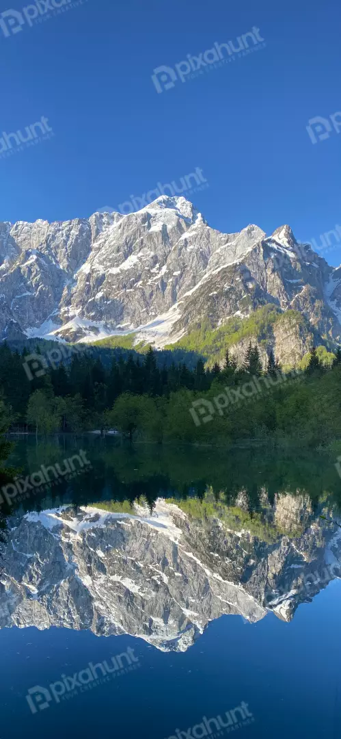 Free Premium Stock Photos Snow-capped mountains reflected in a serene alpine lake under a clear blue sky.
