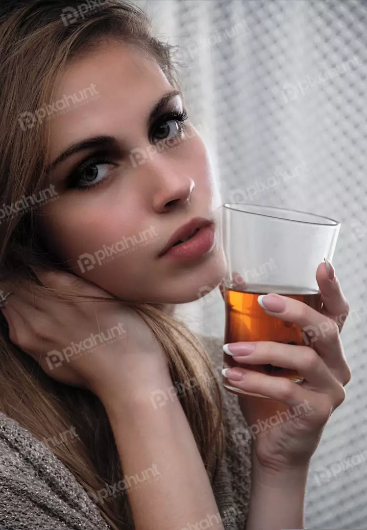 Pensive Woman Holding Amber Drink with Intense Gaze