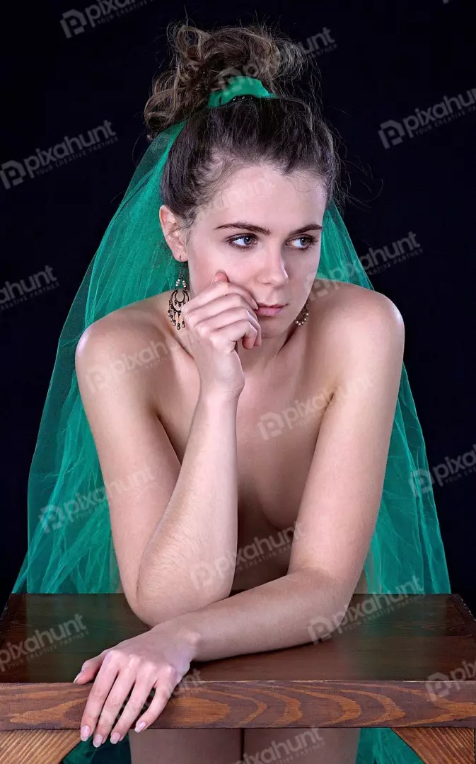 Young woman with green veil posing thoughtfully on dark background