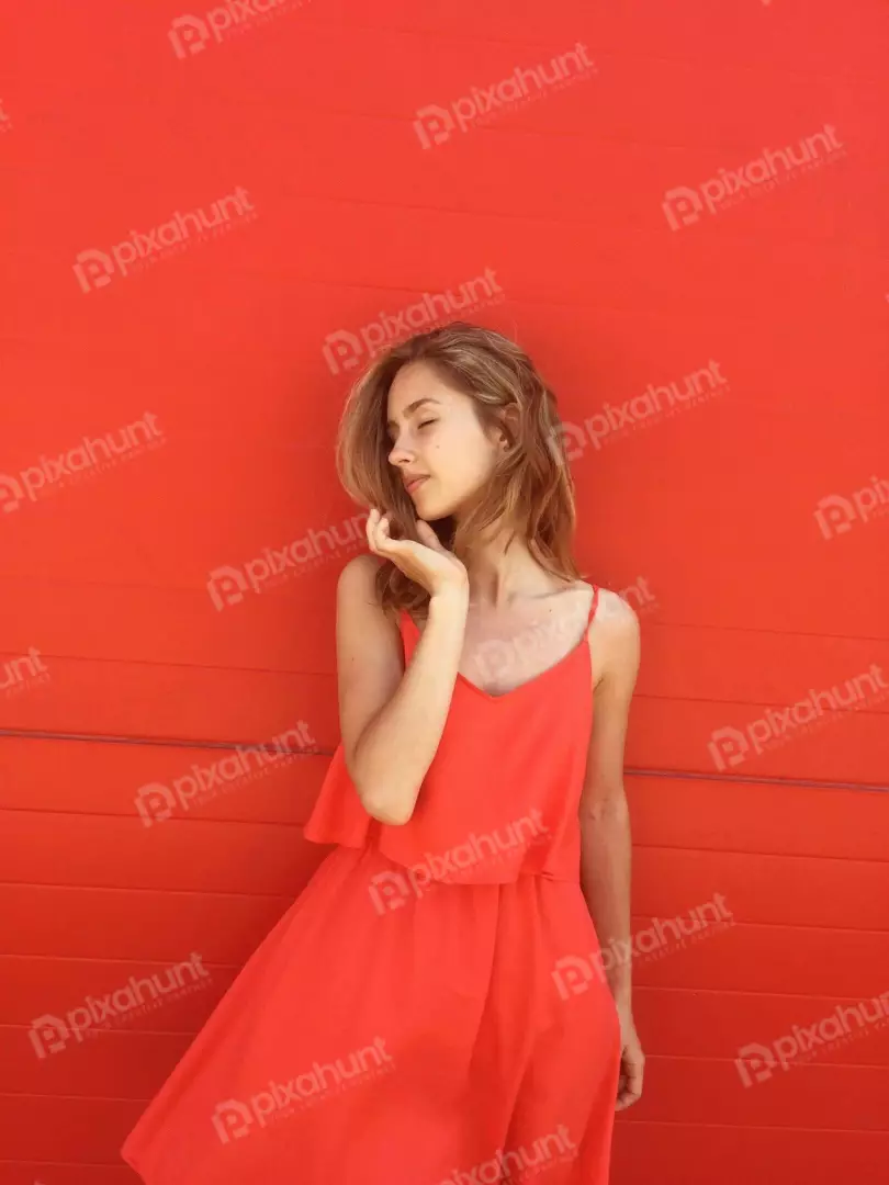 Free Premium Stock Photos Young Woman Enjoys Sun in a Vibrant Orange Sundress Against Red Wall