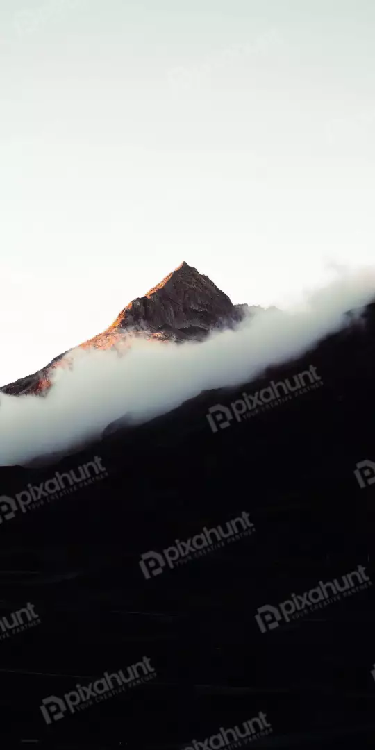 Free Premium Stock Photos Dramatic mountain peak emerges from mist during sunrise