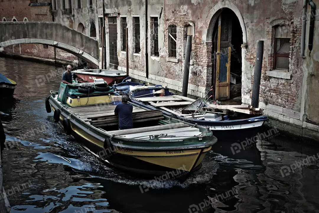 Traditional Boats Navigating a Grungy Venetian Canal Lined with Historic, Weathered Buildings