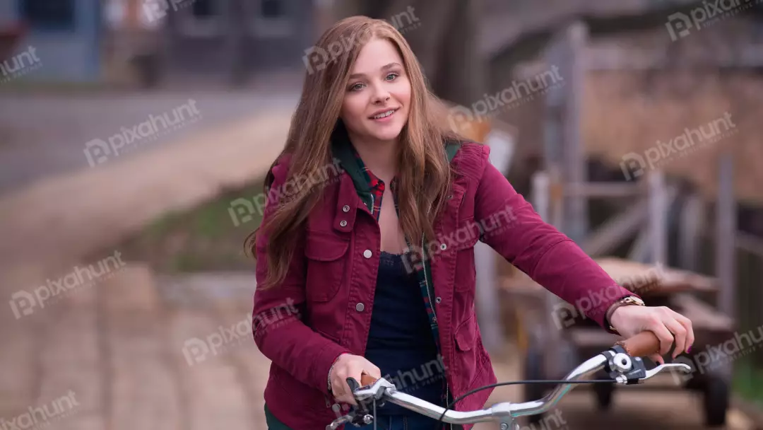 Smiling young woman with long hair and red jacket on a bicycle outdoors