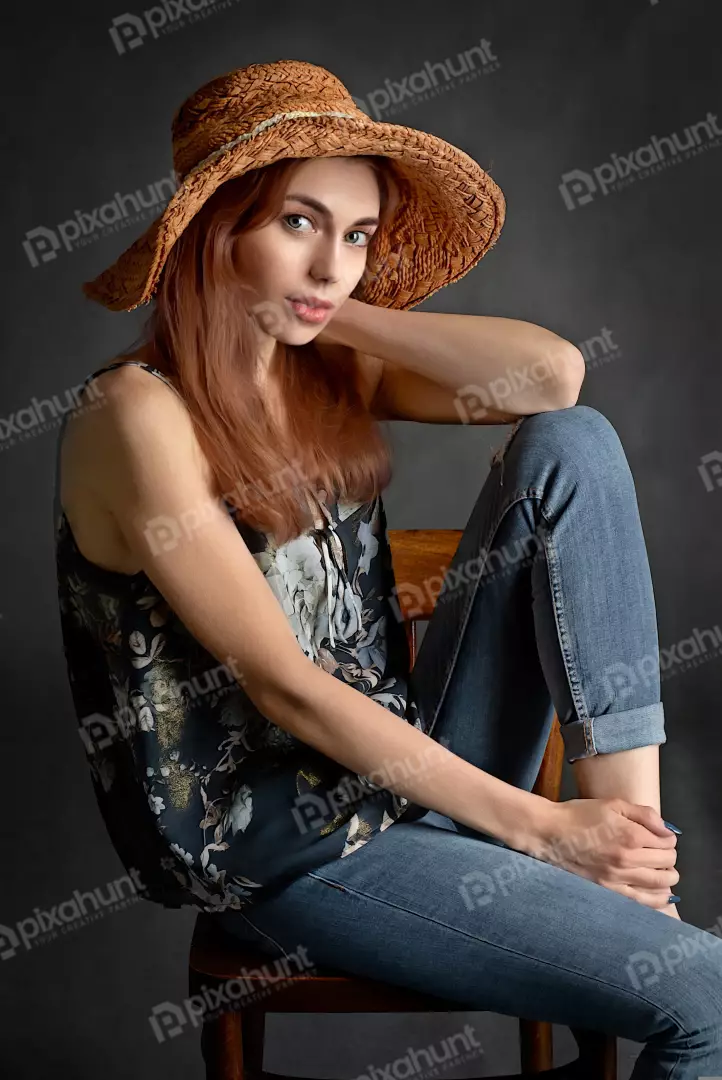 Red-Haired Woman Posing with Straw Hat and Floral Top in Studio
