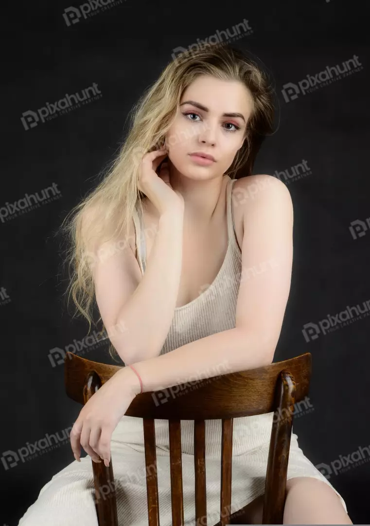 Young Blonde Woman Sitting on Wooden Chair in Contemplative Studio Portrait