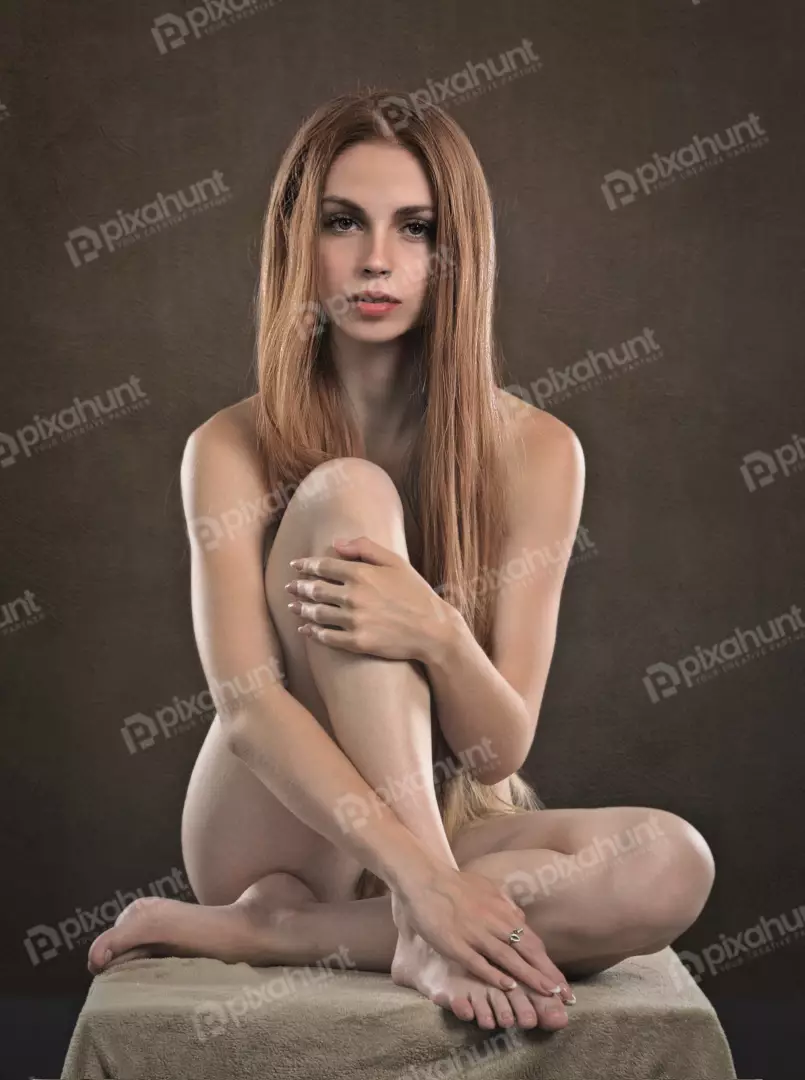 Nude Woman with Long Auburn Hair in Serene Seated Studio Portrait