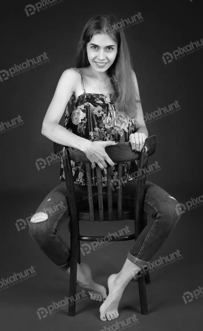 Smiling Young Woman Posing on Wooden Chair in Ripped Jeans