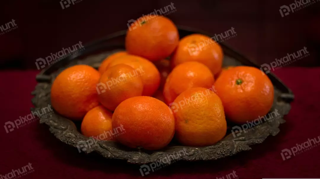 Fresh Orange Tangerines in Rustic Metal Bowl on Deep Red Fabric