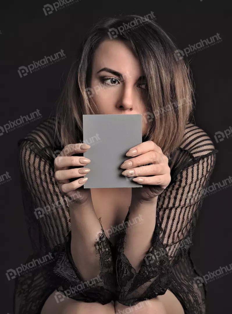 Intriguing woman in black lace holding blank grey card for design element