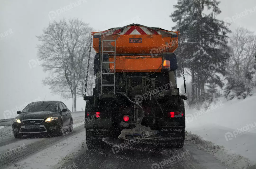 Orange Road Salt Spreader Truck Actively Working on Snowy Winter Highway