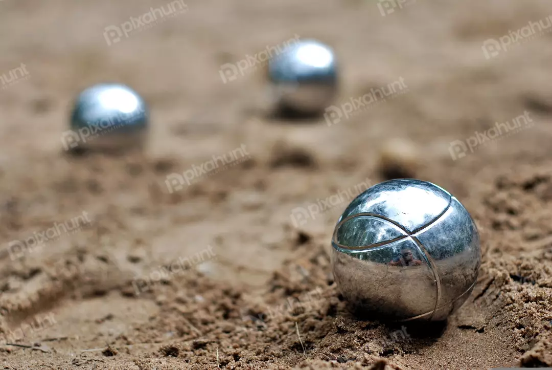 Close-up of Shiny Metallic Pétanque Boules Resting on Sandy Ground for Outdoor Game