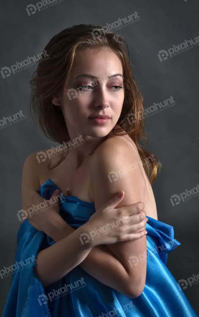 Pensive Young Woman Holding Shimmering Blue Fabric in Elegant Pose