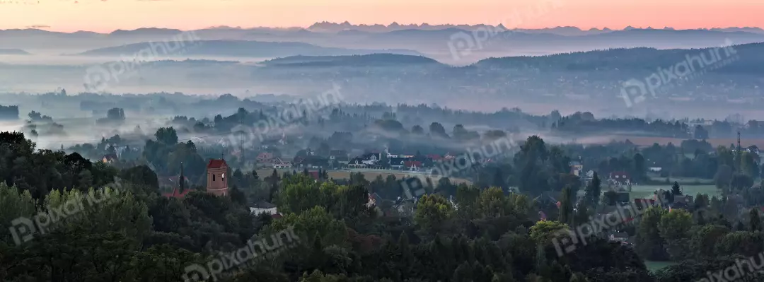 Dawn Mist Panorama: European Village Nestled in Foggy Mountain Landscape