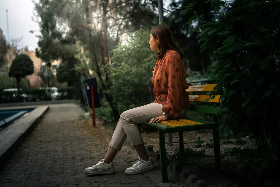 Free Premium Stock Photos Woman in patterned blouse and light pants sits on a park bench