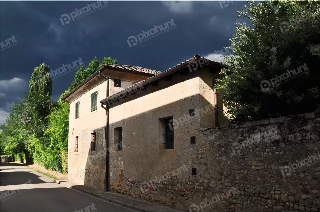 Historic European Stone House Under Dramatic Sky with Sunlit Facade