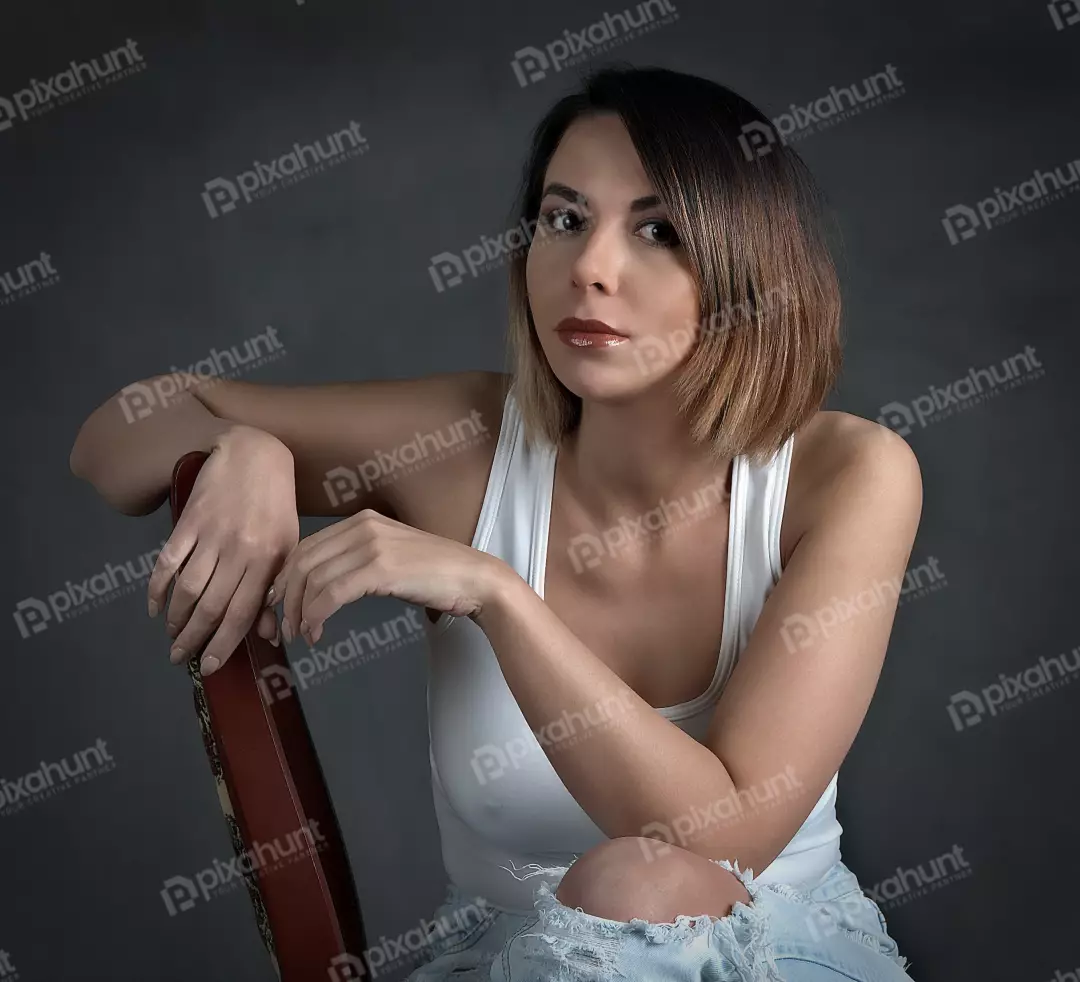 Confident Young Woman in Casual White Tank Top and Ripped Jeans Posing