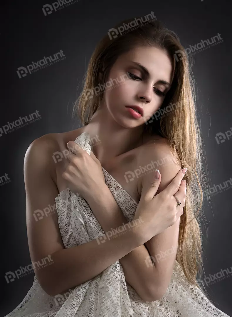 Pensive Young Woman Draped in White Lace Fabric on Dark Background