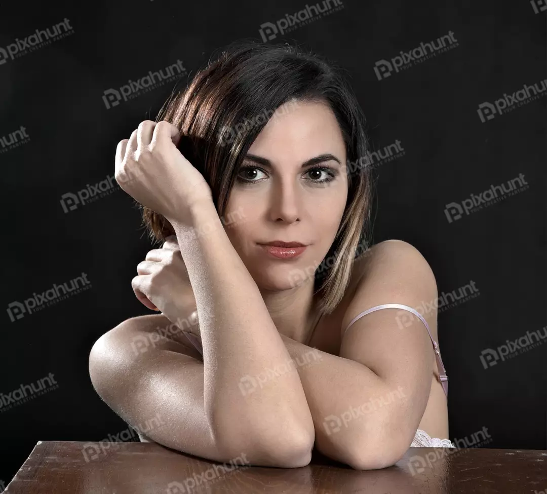 Captivating Young Woman Posing Gracefully, Leaning on Table with Pensive Gaze