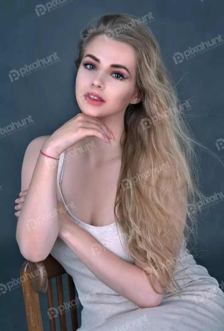 Young Blonde Woman Posing Thoughtfully on Wooden Chair in Studio