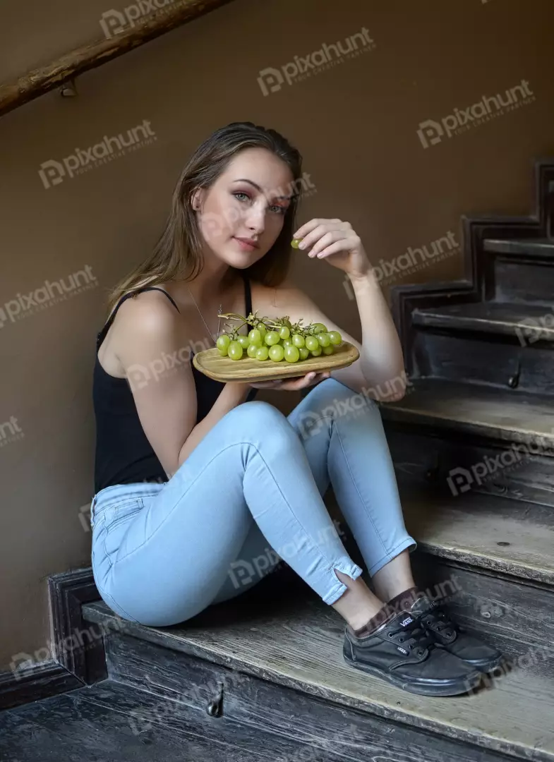 Smiling Young Woman Eating Fresh Grapes on Rustic Wooden Stairs
