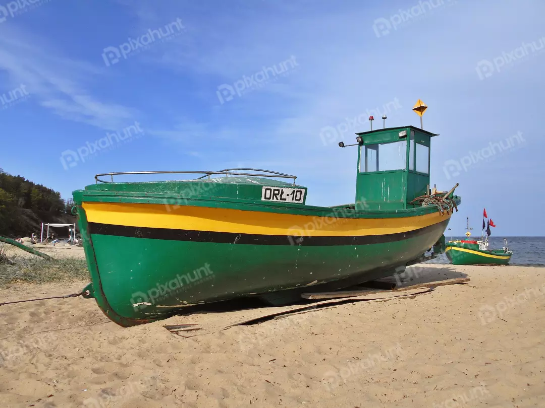 Traditional Green and Yellow Fishing Boats Resting on a Sunny Sandy Beach Shore