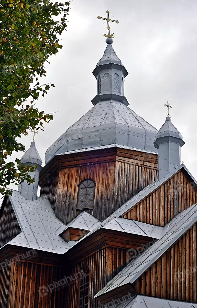 Historic Wooden Church Architecture with Metal Roof and Golden Crosses Against Cloudy Sky