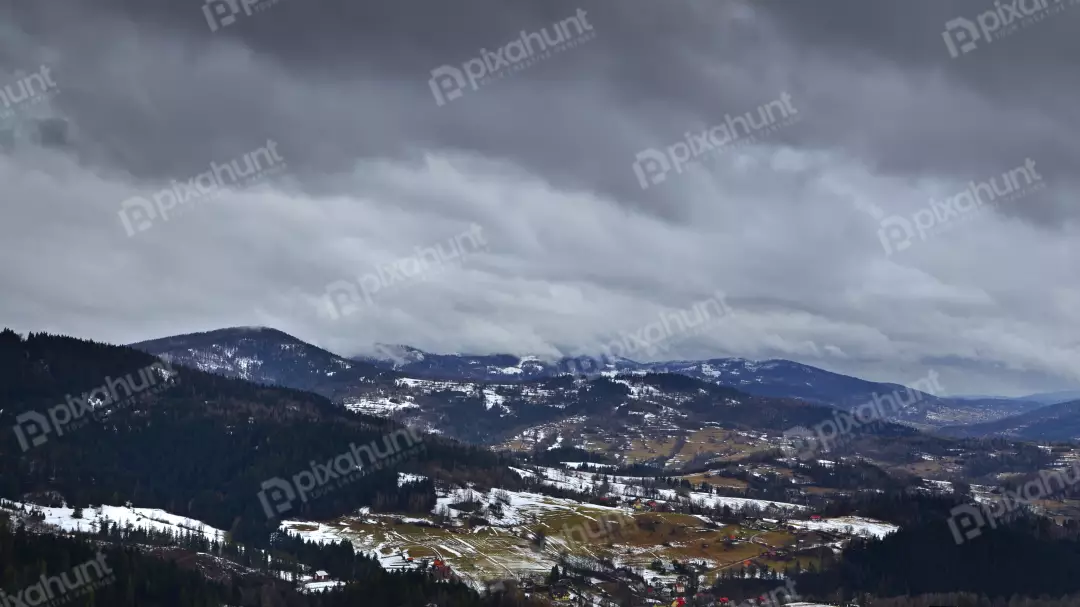 Cloud-Covered Mountains with Patches of Snow and Scattered Settlements