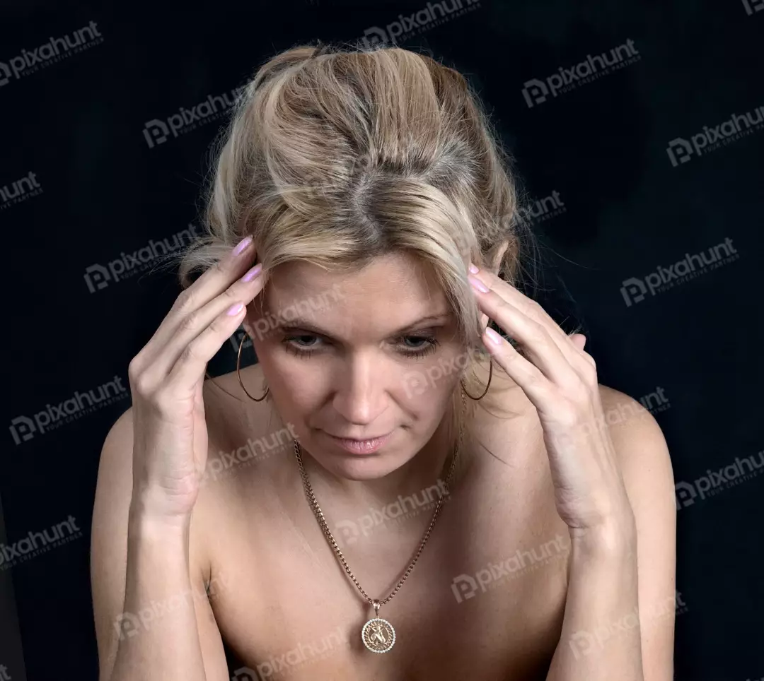 Pensive Blonde Woman with Hands on Temples Portraying Emotional Stress on Black Background