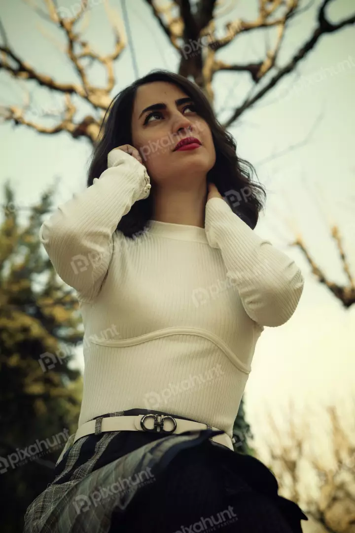Free Premium Stock Photos Stylish Woman in White Ribbed Top & Plaid Skirt Contemplatively Looks Up Amidst Autumn Trees