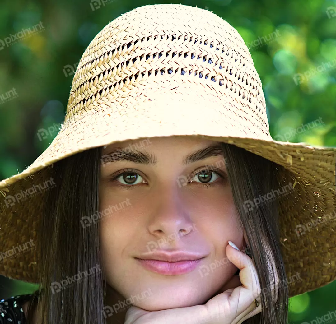 Beautiful Young Woman in Straw Hat Posing with Hand on Chin