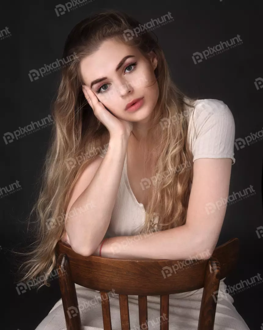 Contemplative Blonde Woman on Wooden Chair with Pensive Gaze
