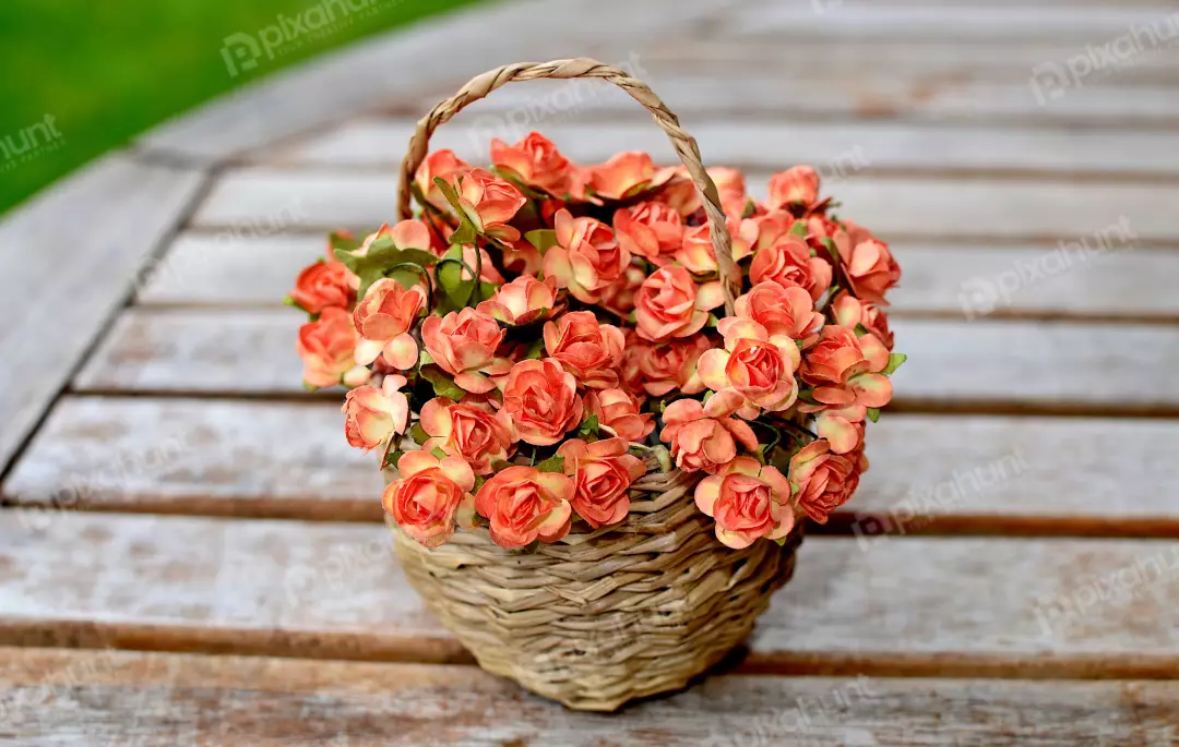 Wicker Basket Filled with Orange Pink Artificial Flowers on Rustic Wooden Table