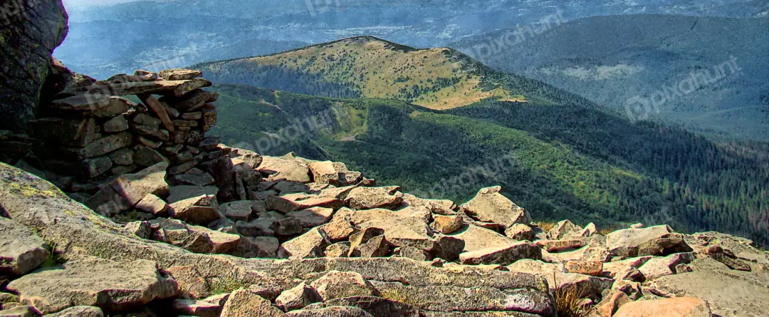 Rugged Mountainous Landscape with Rocky Foreground and Lush Green Forests