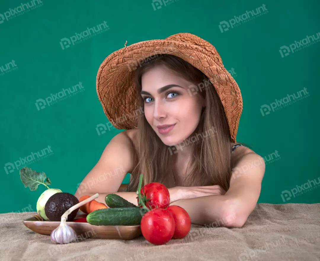 Smiling Young Woman in Straw Hat Posing with Fresh Garden Vegetables