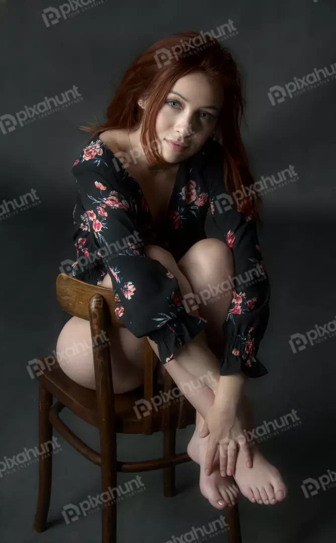 Young Redhead Woman Posing Elegantly in Floral Top on Wooden Chair