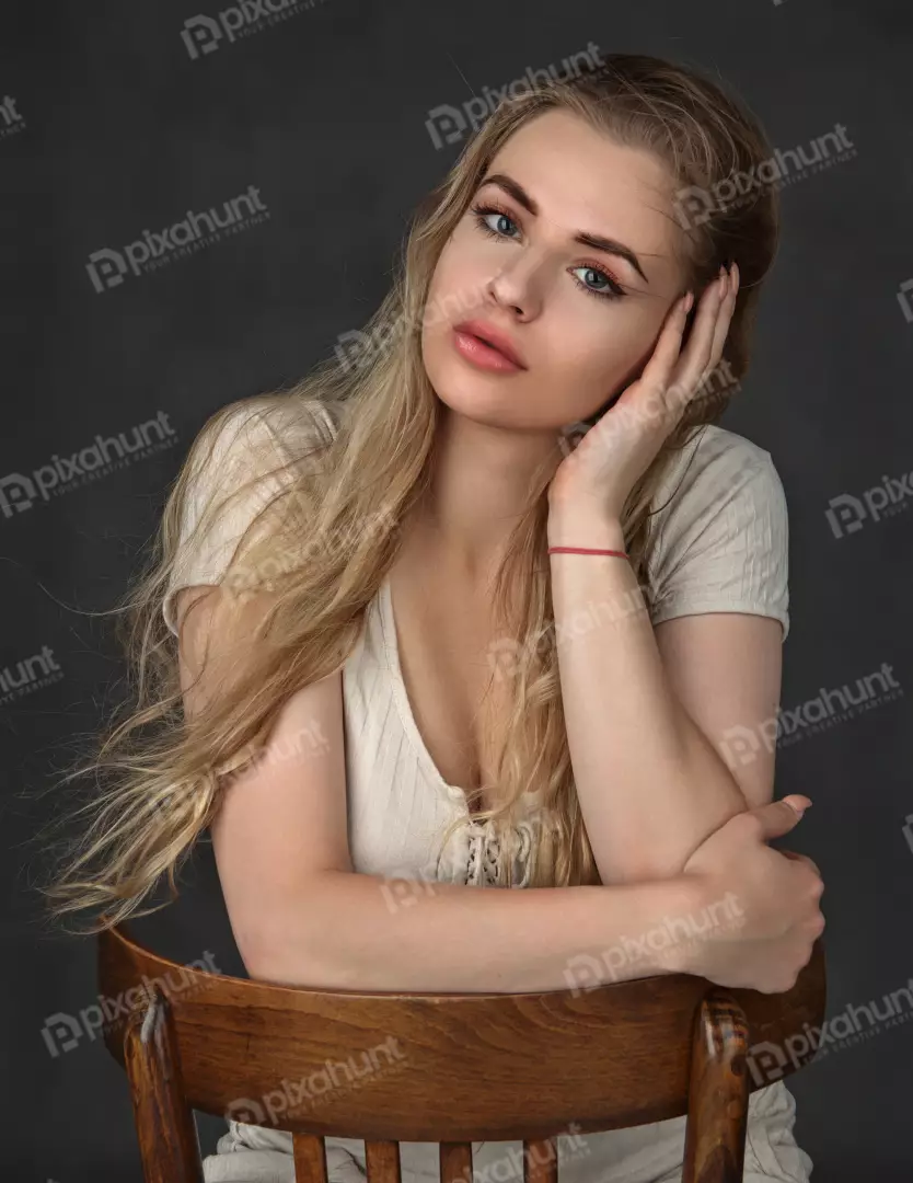 Elegant Blonde Woman Posing Thoughtfully on Wooden Chair