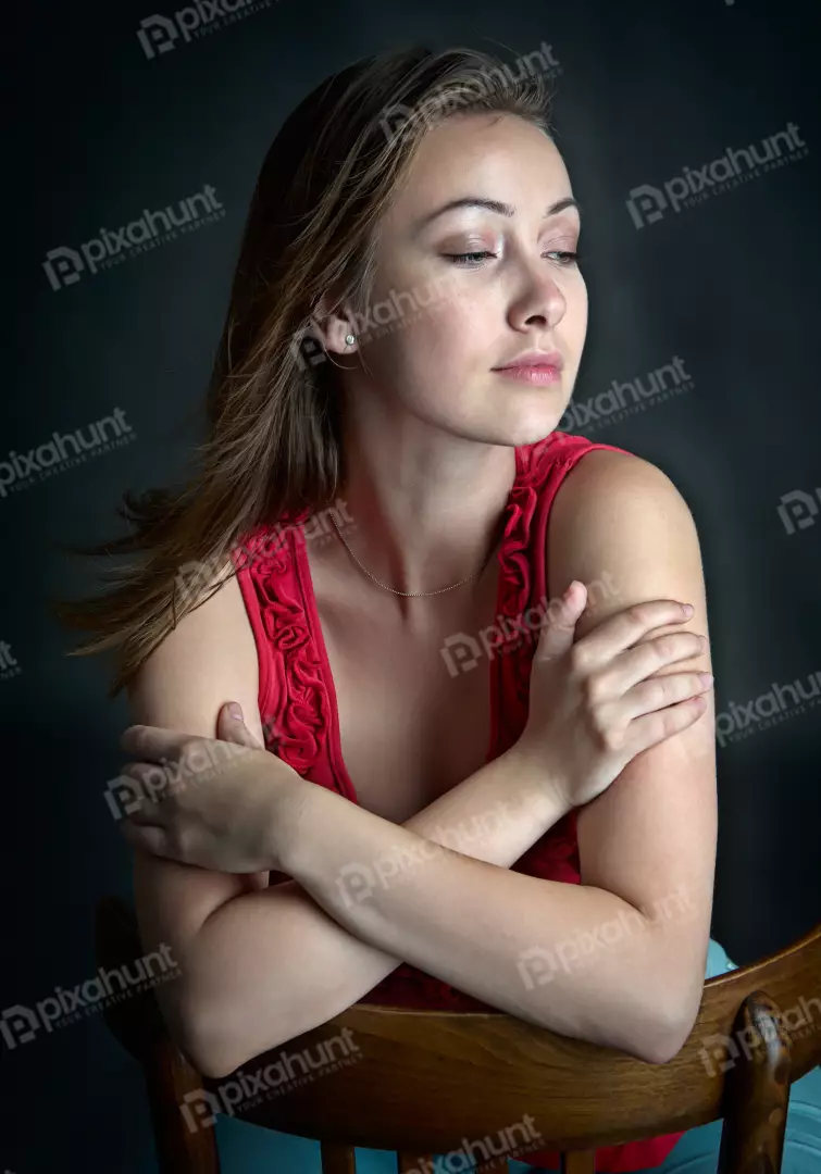 Pensive Young Woman with Crossed Arms in Red Top on Wooden Chair