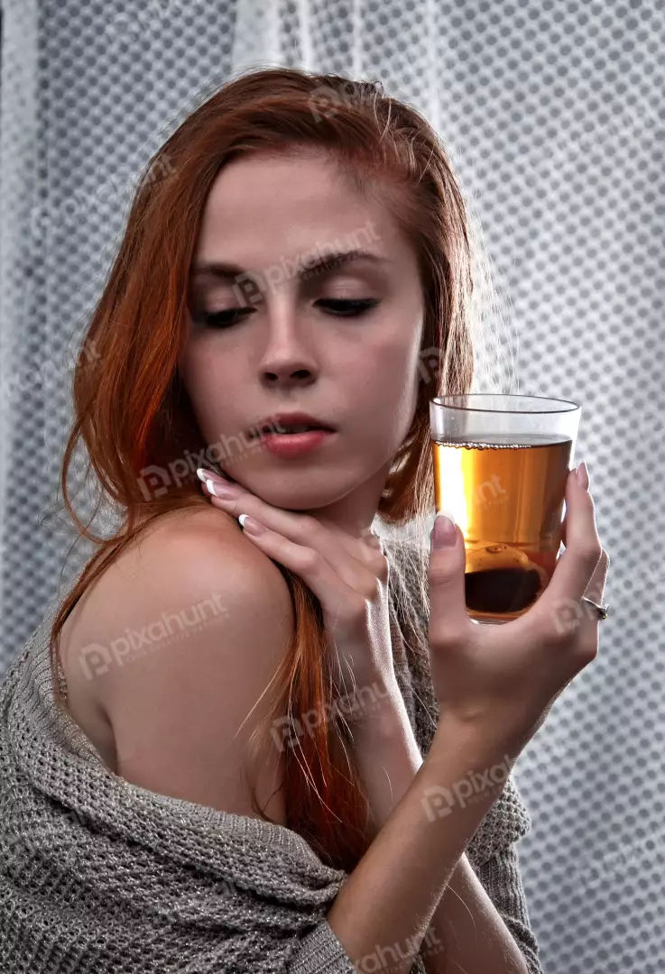 Elegant Red-Haired Woman Holding Amber Beverage in Contemplative Pose