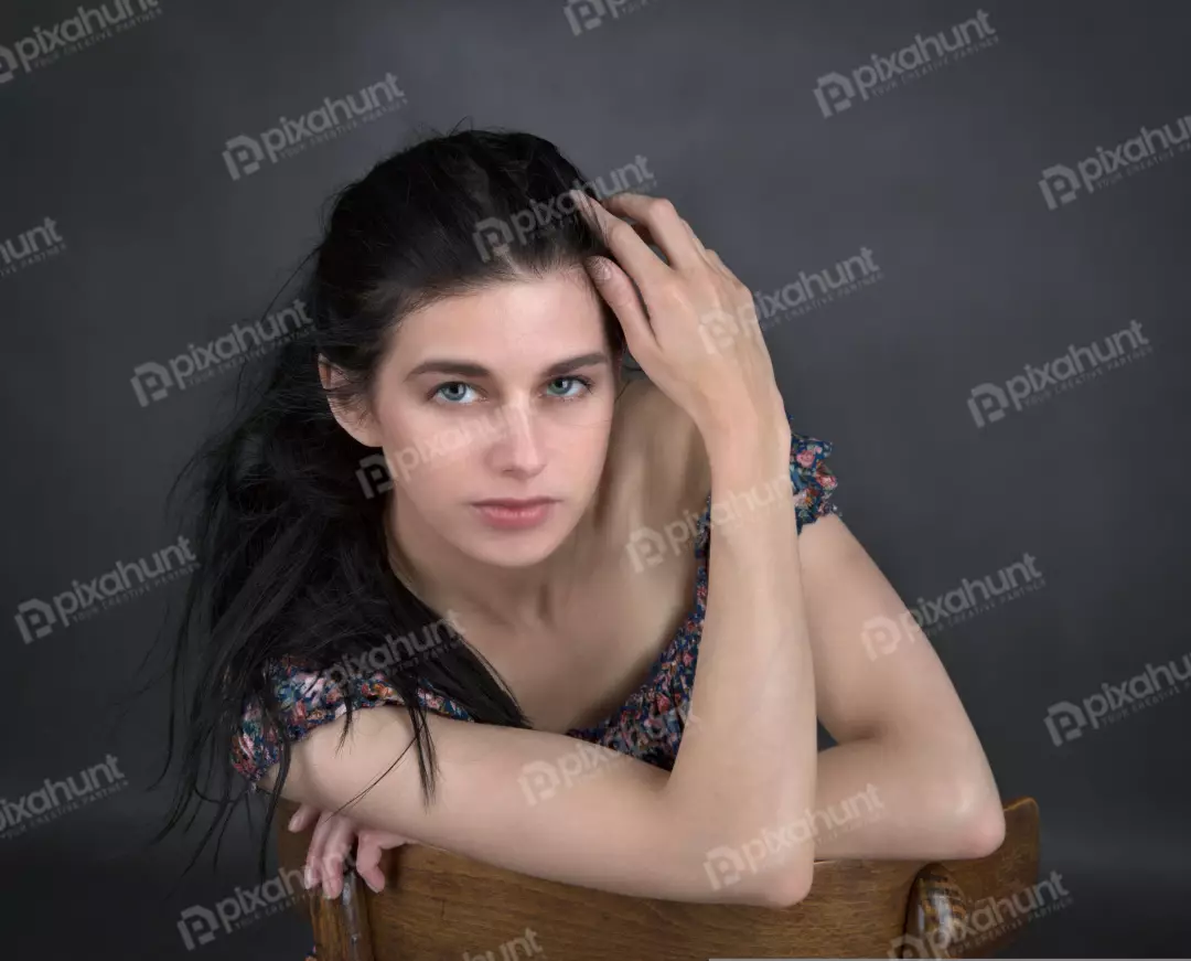 Pensive Young Woman with Dark Hair and Blue Eyes, Hand in Hair, Studio Portrait
