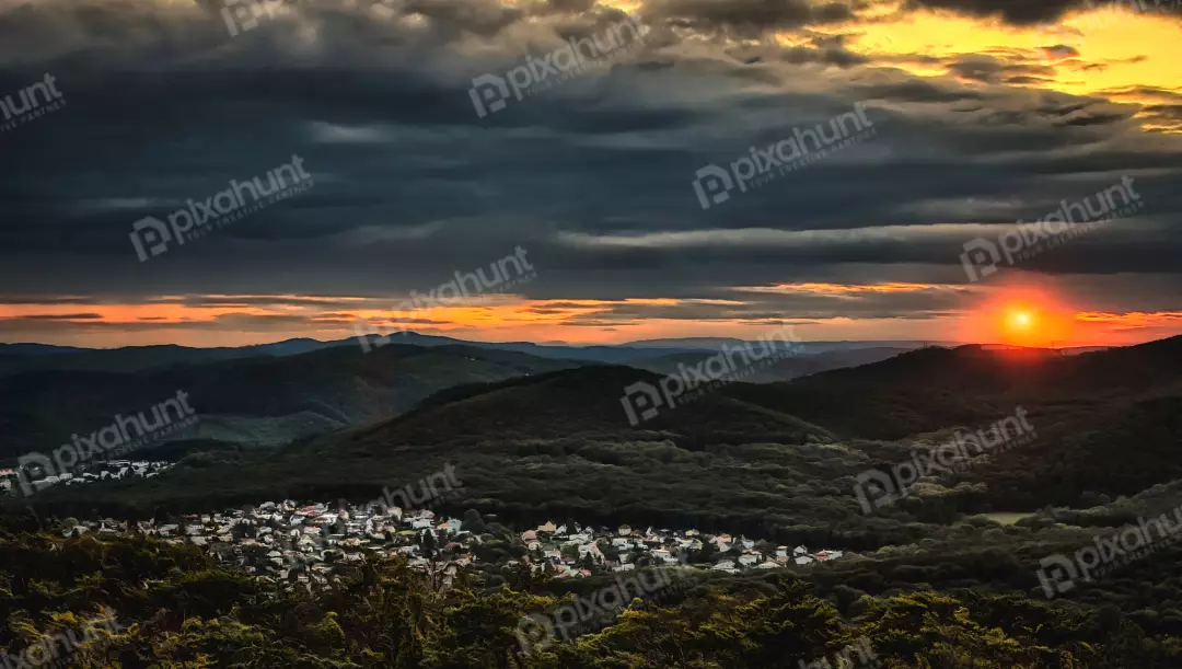 Dramatic Sunset Over Forested Hills and Village with Golden Hour Sky