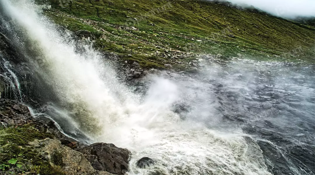 Powerful Waterfall Cascading Down Green Rocky Mountain Landscape with Mist