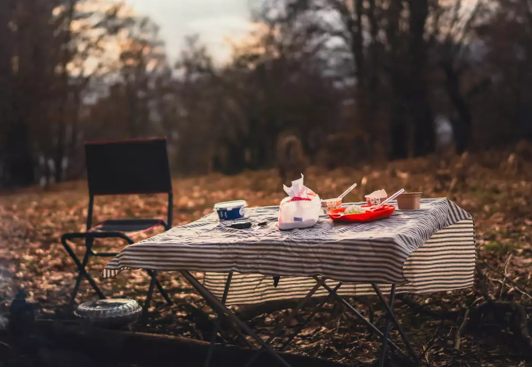 Free Premium Stock Photos Camp picnic table with food and chair in autumn forest at sunset