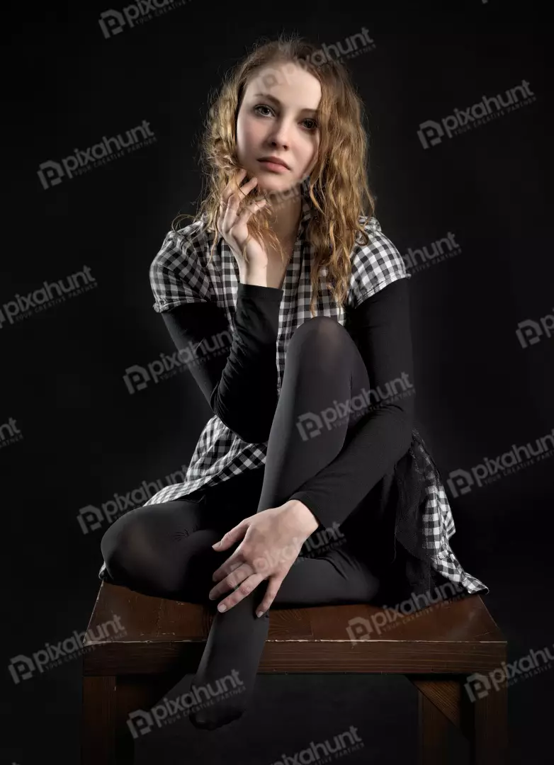 Pensive Young Woman with Curly Hair and Checkered Blouse on Dark Background