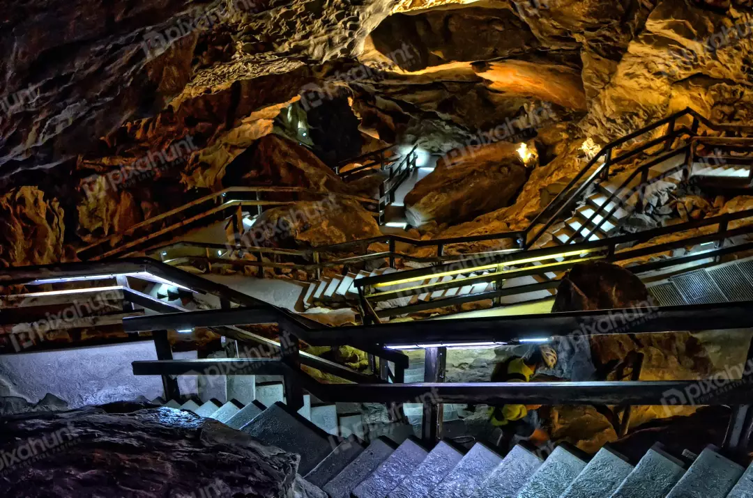 Illuminated Underground Cave with Tourist on Winding Stairs