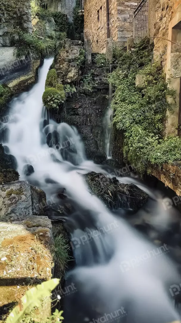 Free Premium Stock Photos Silky smooth waterfall cascading over mossy rocks and stone buildings