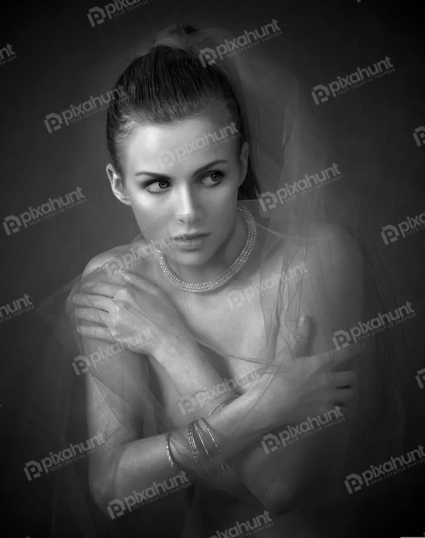 Contemplative Young Woman in Classic Black and White with Sheer Veil and Pearl Jewelry