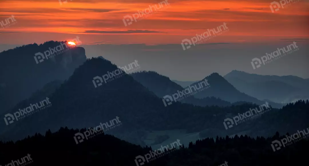 Vibrant Mountain Sunset Over Layers of Peaks and Forest Horizon